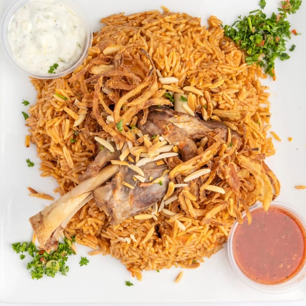 Middle-Eastern lamb shank with rice, fried onions, almonds, and two dipping sauces.